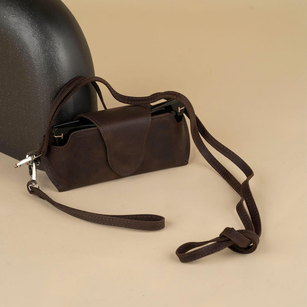 Dark brown leather sunglass case with wrist strap by LEATHERE, designed for eyewear accessories, shown with open and closed views.