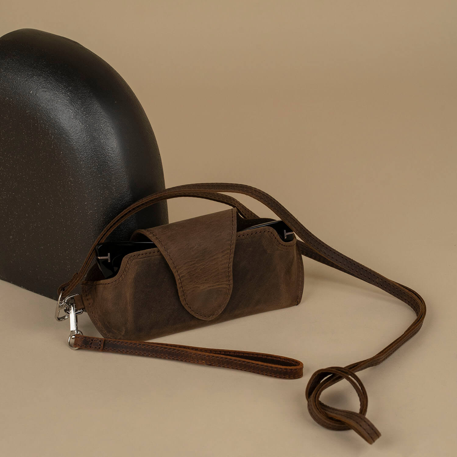 Rich dark brown leather sunglass case with wrist strap by LEATHERE, designed for eyewear accessories, shown with the case open.
