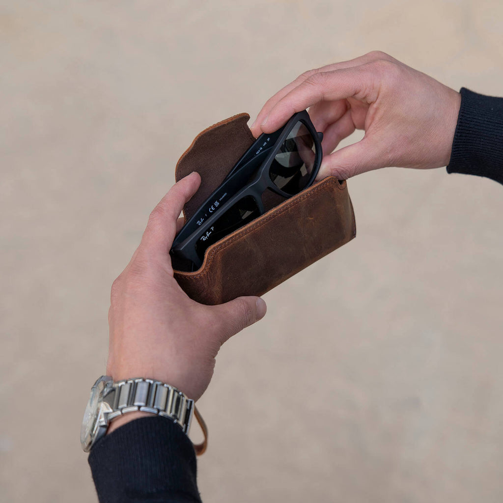 Rich dark brown LEATHERE leather sunglass case with wrist strap, designed for eyewear protection and convenience.