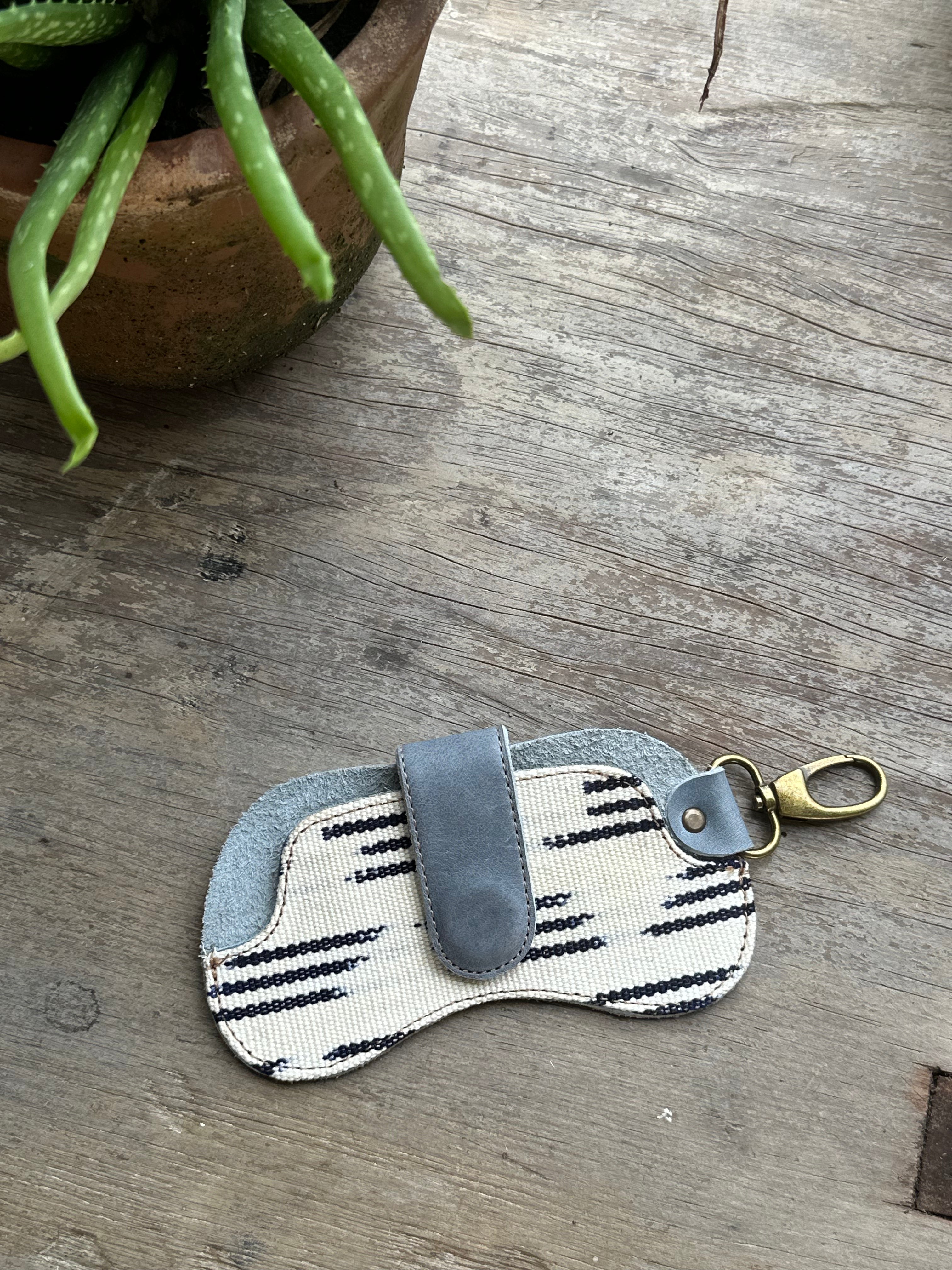 Black striped sunglass case from IXCHELTRIANGLE, an eyewear accessory designed to protect and store sunglasses.