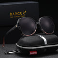 Stevvex BARCUR oversized polarized UV400 sunglasses with black frames and dark tinted lenses, reflecting sunlight outdoors.
