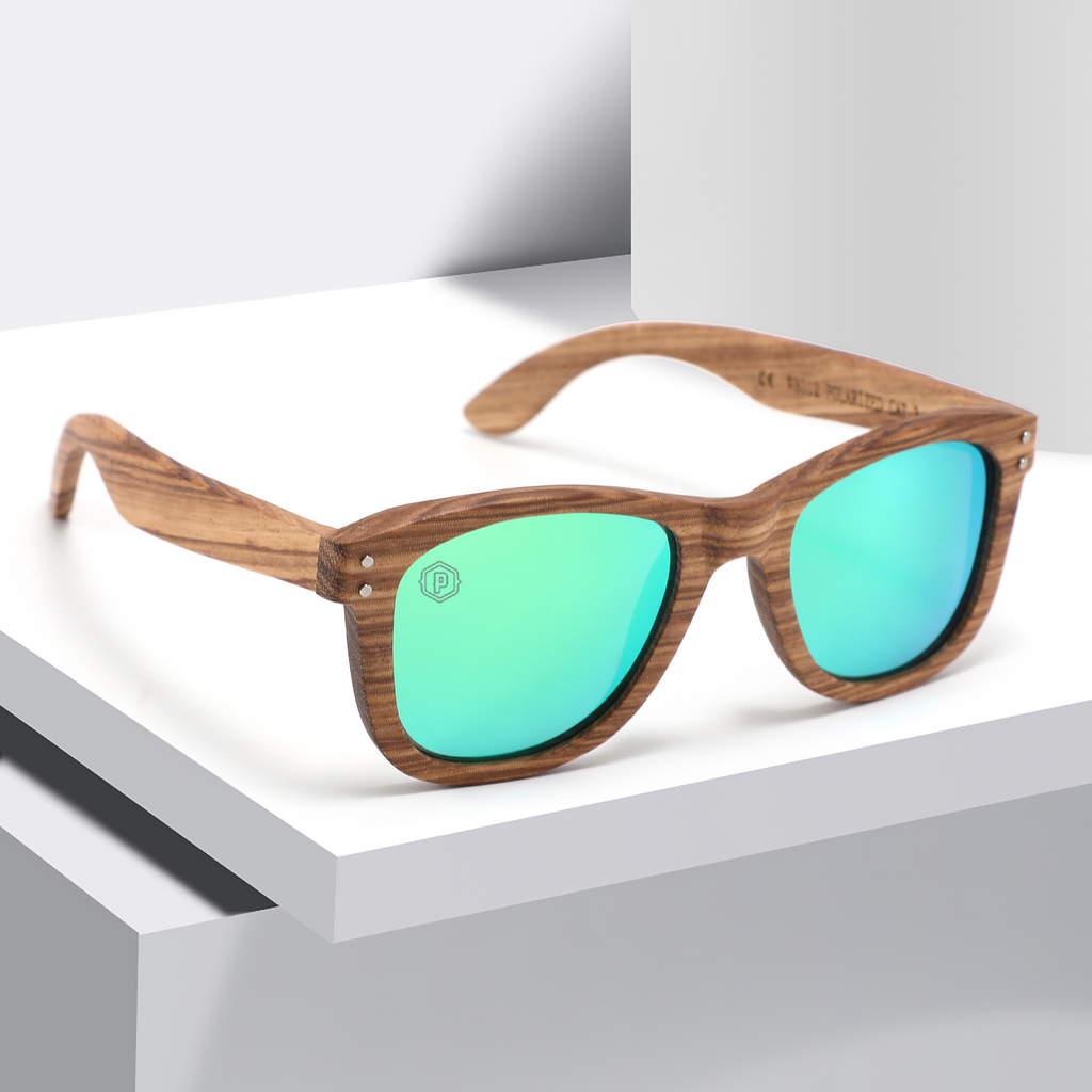 Papago Emerald Dunes sunglasses resting on a book, handmade recycled wooden frames with green-tinted lenses.