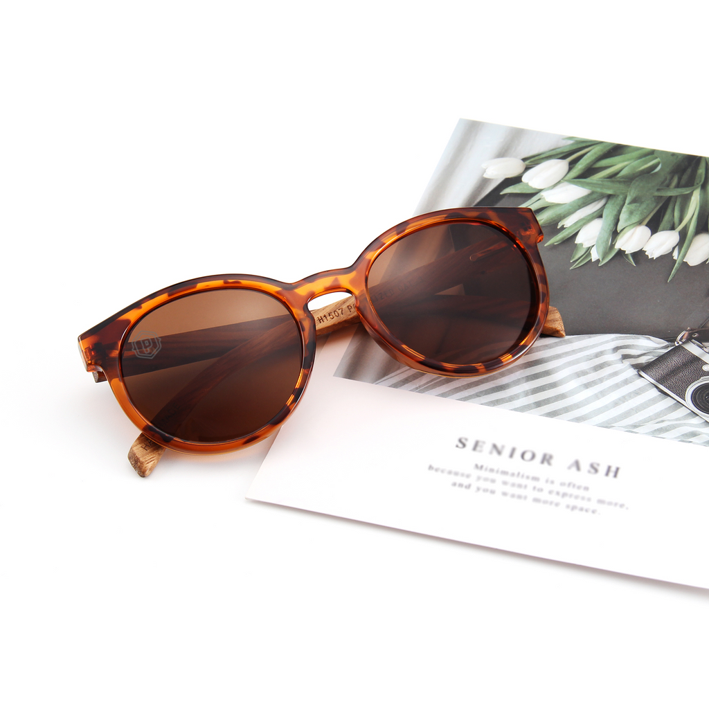 Papago Tortoise Lidos sunglasses with handmade recycled wooden frames, shown lying down with a mag background.